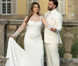 Braut und Bräutigam halten sich vor einer eleganten Schlosskulisse an den Händen. Romantische Hochzeitsfotografie mit professioneller Blitzlicht-Technik von Majestic Wedding in Stuttgart.